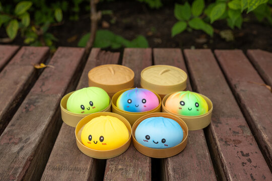 Colorful kawaii dumpling squishy toys in bamboo steamer shaped cases outdoors in daylight