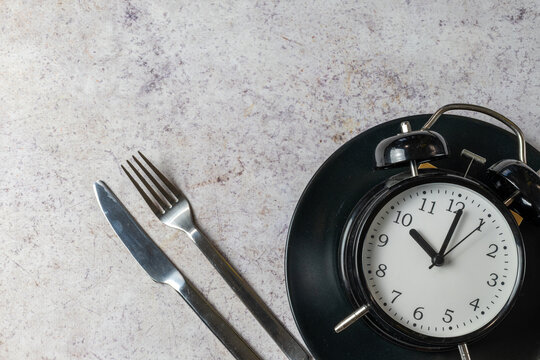 Intermittent Fasting Concept With Alarm Clock And Cutlery