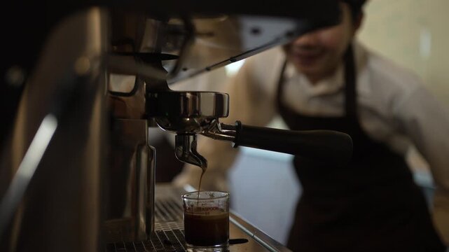 Teen barista trainee watching espresso extract at a coffee shop