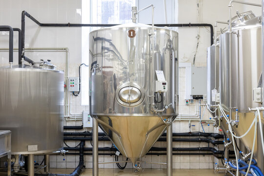 Large stainless steel fermentation tank inside brewery production workshop