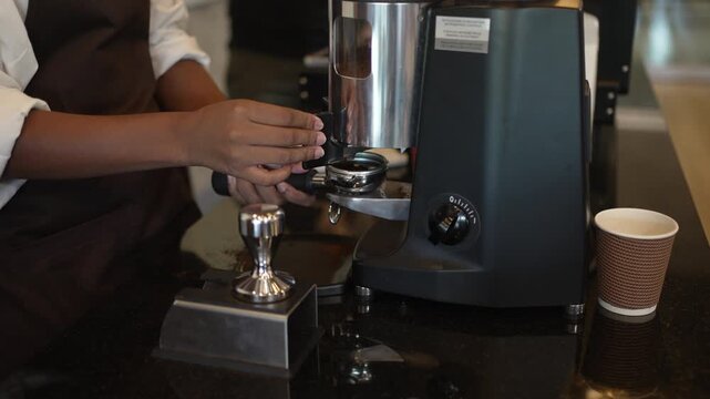 Barista trainee pressing grinder lever to fill a portafilter