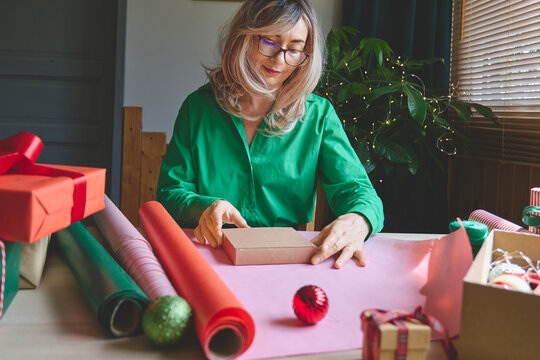 Woman wrapping Christmas gifts at home.
Preparing presents for loved ones reflects holiday shopping, seasonal celebrations, gift giving and the joy of Christmas traditions.