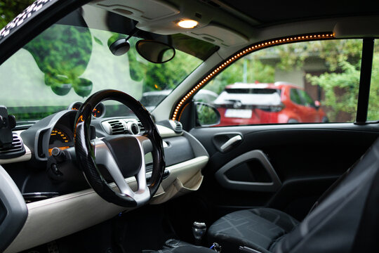 Inside look of an automobile dashboard, steering wheel, and front seats with an open door, showcasing contemporary automotive design and vehicle interior ergonomics.