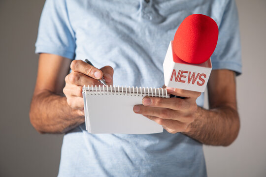 Journalist holding a microphone and notepad.