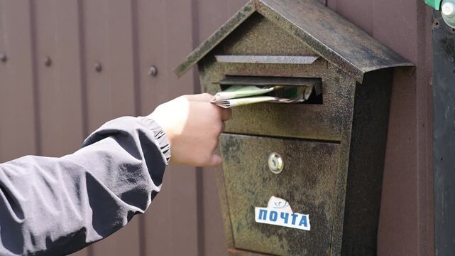 Aged metal mailbox with russian text holds delivered mail. Weathered iron post box is mounted on house wall. daily newspaper delivery. village of Thorin, Zhytomyr region,Ukraine,July 12,2026 editorial