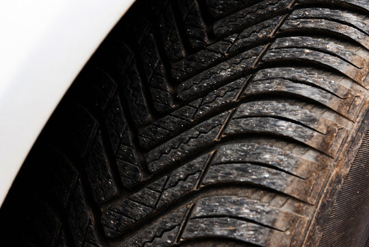 Close-up of a car tire tread pattern with directional grooves.