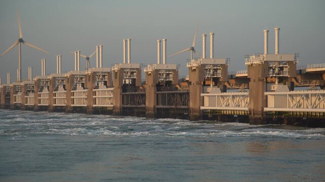 Oosterscheldekering storm surge barrier in Zeeland, Netherlands, with wind turbines visible along the coastal infrastructure and water.