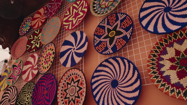 Colorful handmade woven wall baskets are displayed on a terracotta wall in a Moroccan shop. Traditional decoration and souvenirs. The vibrant colors and intricate patterns local craftsmanship.