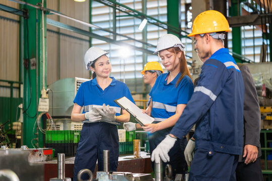 Diverse team of engineers and workers discussing production plans in factory, Professional industrial staff reviewing documents and working together at manufacturing plant
