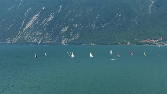 Drone shot of sailing boats racing on Lake Garda, Italy in the summer with huge mountains in the background