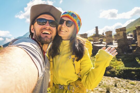 Smiling happy caucasian couple taking selfie by Ushguli svan tower settlement. Hiking in Svaneti Georgia. Man woman backpacking outdoors near historical Unesco world heritage site