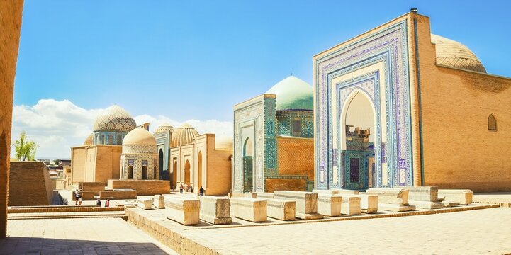 Shah i Zinda necropolis in Samarkand. Visitors explore the stunning blue-tiled mausoleums and turquoise domes of historic UNESCO Silk Road landmark