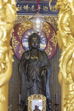 A standing Buddha in front of a richly decorated red mandala radiates quiet dignity and timeless serenity, golden pillars frame the scene like a gateway to inner contemplation and spiritual peace, Chee Chin Khor Temple, Bangkok, Thailand