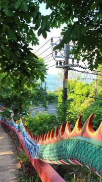 Colorful dragon scale fence railing along a roadside path with trees and power