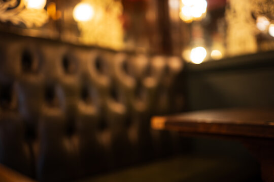 London, England, United Kingdom, August 14, 2026. Defocused interior view of a dark leather pub booth and table.
