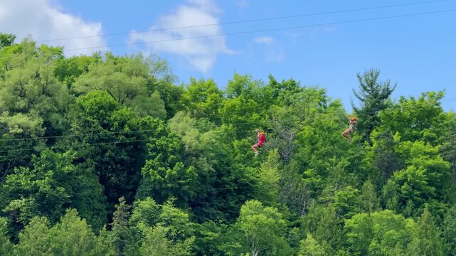 People ziplining over Montmorency Falls beneath a suspension bridge in Quebec City, Quebec, Canada.