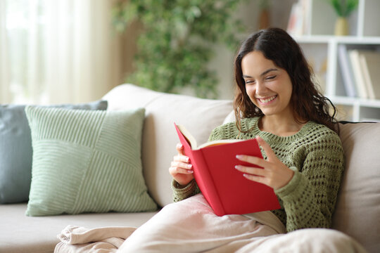Happy woman reading a paper red book in winter at home