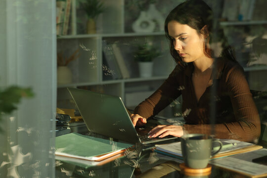 Serious young telecommuter working at home writing on laptop