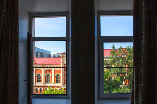 Charming view of a historic red roof building seen through open indoor windows in the sunny morning in Saint Petersburg, Russia.