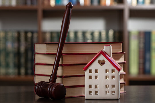 A judge's gavel and a symbolic house set against a backdrop of bookshelves.