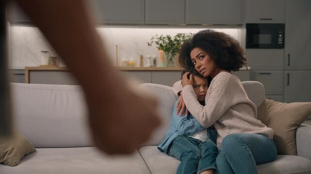Domestic violence African American angry drunk man abuser beating wife room home back view unknown father husband fist afraid woman hiding little boy child kid son indoors marriage harassment problem