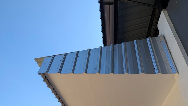 Silver metal corrugated roof eave edge against clear blue sky