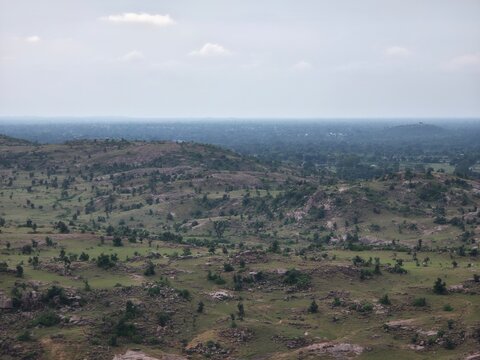 A wide panoramic view reveals scattered rocks and vegetation.