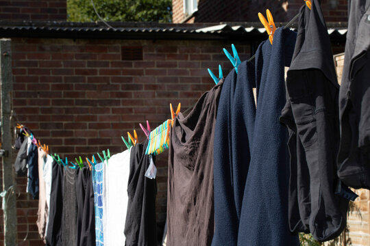 Clothes pegs and laundry garments hanging on a single long washing line being held up by pegs, tradition drying method