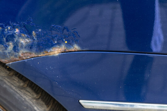 Close-up of rusty car body with damaged paint and poor accident repair