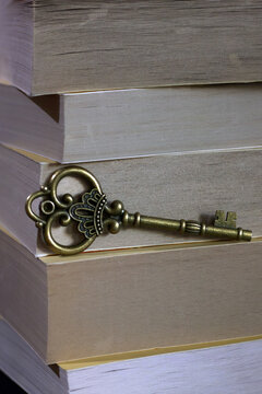An ornate vintage key rests on stacked books. The composition represents knowledge, secrets, access and the discovery of hidden stories