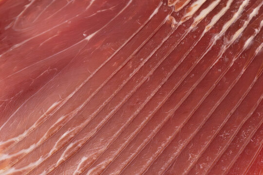 Jamon serrano. A Spanish ham texture background. Traditional spanish jamon sliced. Dry cured meat ham. Hamon iberico