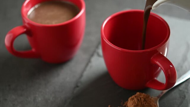 Close-up of hot chocolate being poured into a cup on a table, creating a cozy and comforting scene perfect for winter, holidays, and warm seasonal beverages.