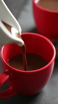 Close-up of hot chocolate being poured into a cup on a table, creating a cozy and comforting scene perfect for winter, holidays, and warm seasonal beverages.