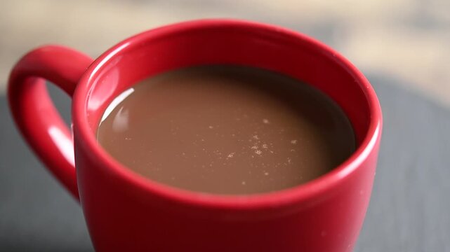 Rotating cups of hot chocolate on wooden table