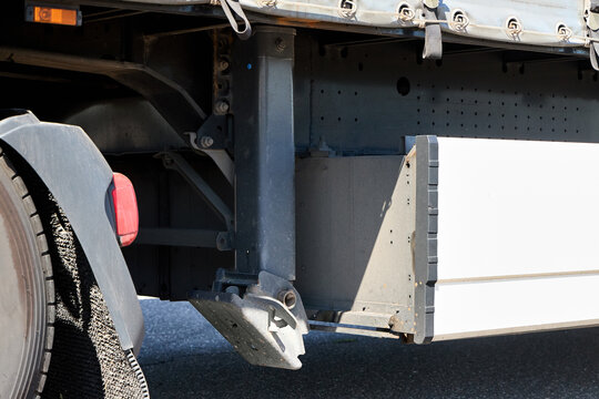 Detailed close-up view focusing on underride guard and support leg structure located beneath side profile of standard commercial semi-trailer unit, showcasing important safety features.