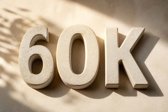 Large, three-dimensional white letters spelling "60K" are displayed against a sunlit, textured wall.
