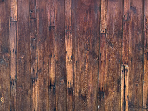 Rustic dark brown wooden planks with visible grain, knots and aged repairs.