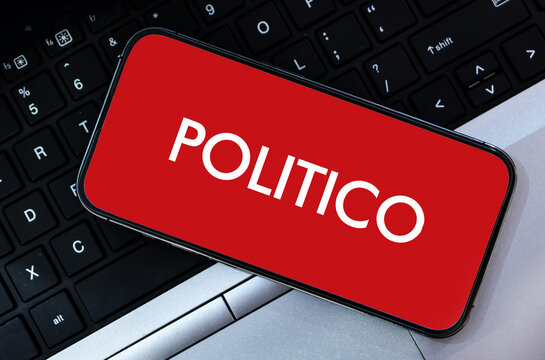 Illustrative editorial showing politico logo on mobile screen over laptop keyboard background