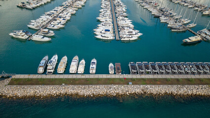 Direct overhead drone view over turquoise marina waters showing rows of white yachts, floating houseboats, and boats docked along piers in Novigrad Istria © POV_artist