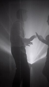 1920s old style black and white color silhouette romantic happy couple dancing together in dark night club. woman flapper with man have fun at dance floor retro party roaring twenties. vertical video