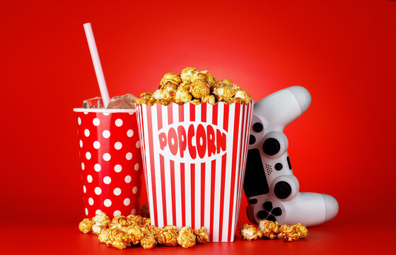 Popcorn, cola and gamepad on red background