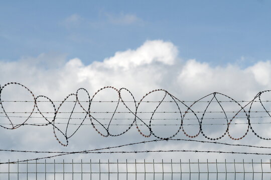 Razor Wire Coils Against Cloudy Sky
