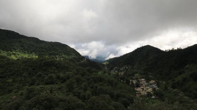 A high-definition timelapse capturing fast-moving monsoon clouds rolling over the lush green mountains, valleys, and rural landscapes of Narayan Nagar and Char Khet in Uttarakhand, India.