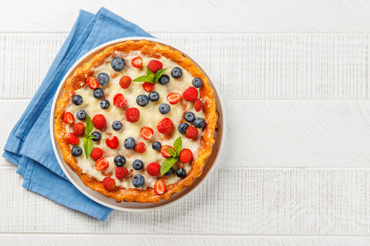 Homemade berry tart topped with fresh raspberries and blueberries