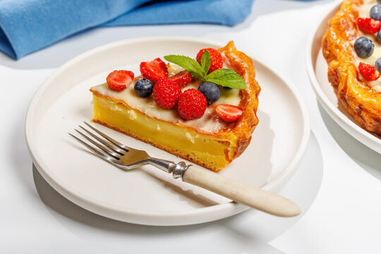 Slice of berry tart served on plate beside whole pie