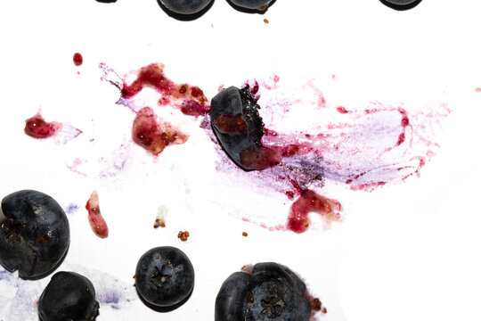 Squashed and crushed blueberries fruit berries splattered on a white background with juice