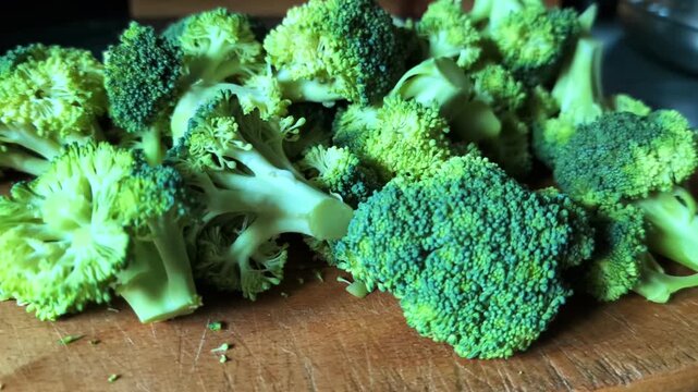 Fresh green broccoli florets arranged on wooden cutting board, close up smooth pan right motion showcasing raw organic vegetables for healthy eating visual storytelling.
