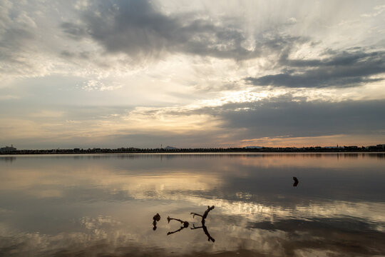 Calm sea at sunset with dramatic cloudy sky reflections on the water surface