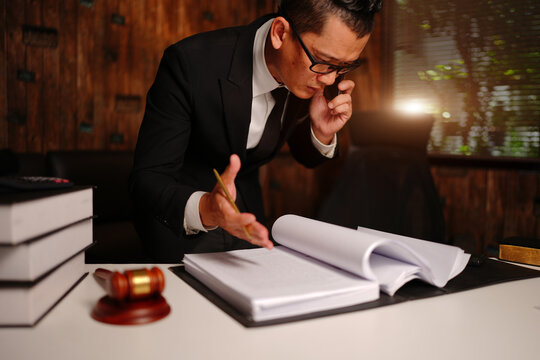 Lawyer Talking on Phone while Reviewing Legal Documents with Gavel on Desk