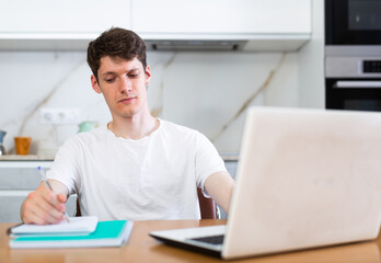 Fototapeta premium Young guy studying at home with laptop